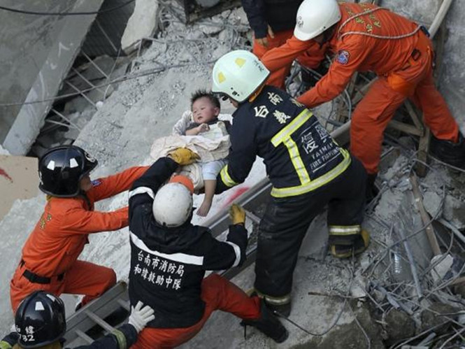 Lực lượng cứu hộ giải thoát cho một đứa bé trong khu chung cư 17 tầng sau trận động đất ở Đại Nam (Đài Loan) hôm 6.2 - Ảnh: AFP