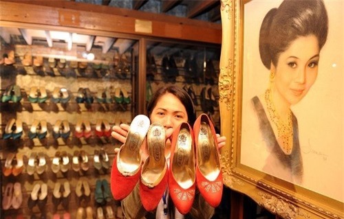 Một nhân viên bảo tàng cho khách xem một số đôi giày của chính vợ phó tổng thống Imelda Marcos, cạnh bức chân dung vẽ bà trong bảo tàng giày ở Manila. Ảnh: Ted Ajibe.