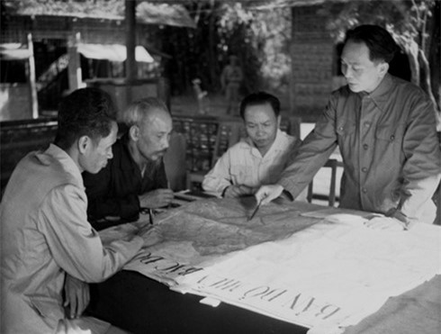 Đại tướng Võ Nguyên Giáp (đứng, bên phải) trình bày với Chủ tịch Hồ Chí Minh và các đồng chí lãnh đạo Đảng, Nhà nước bàn kế hoạch mở chiến dịch Điện Biên Phủ năm 1954 (Ảnh: Tư liệu TTXVN)