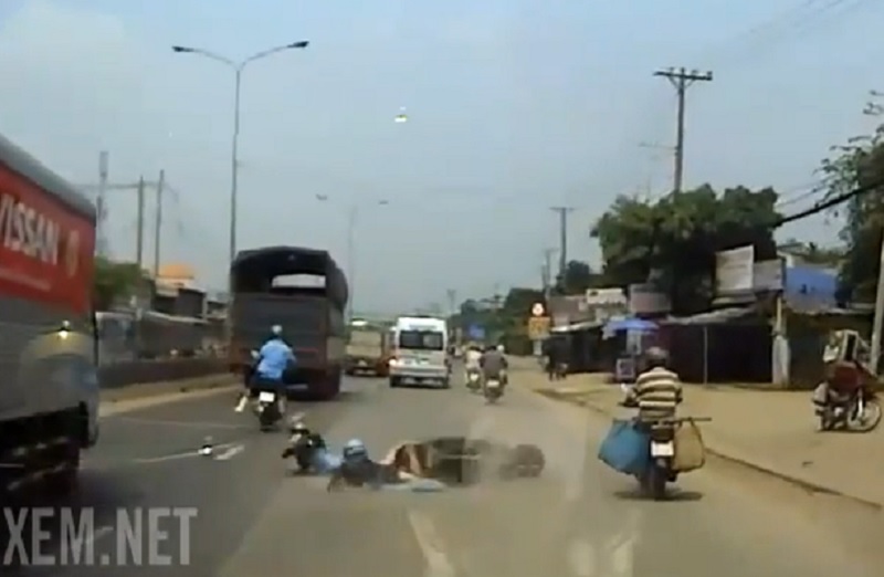 Hai người điều khiển xe máy ngã văng xuống đường sau vụ va chạm.