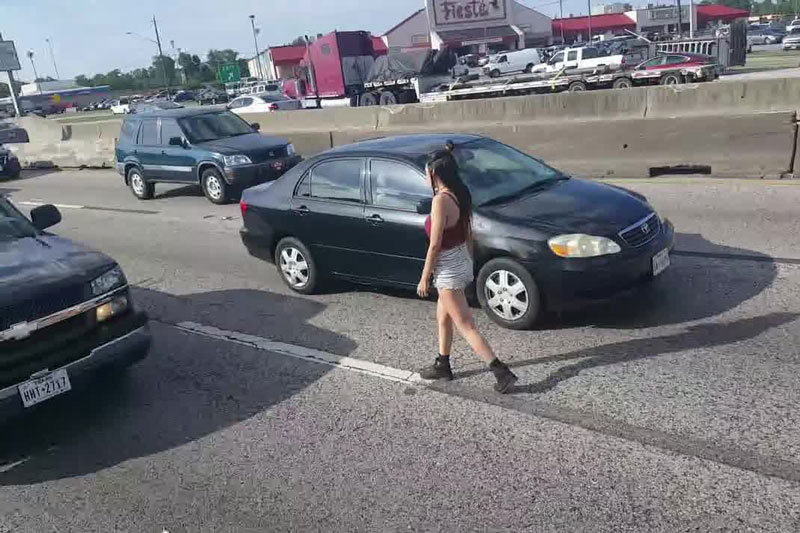 Cô gái trẻ thản nhiên đi bộ ngược chiều trên đường cao tốc.