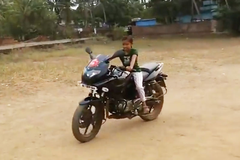 Bé gái điều khiển môtô trên sân bóng.