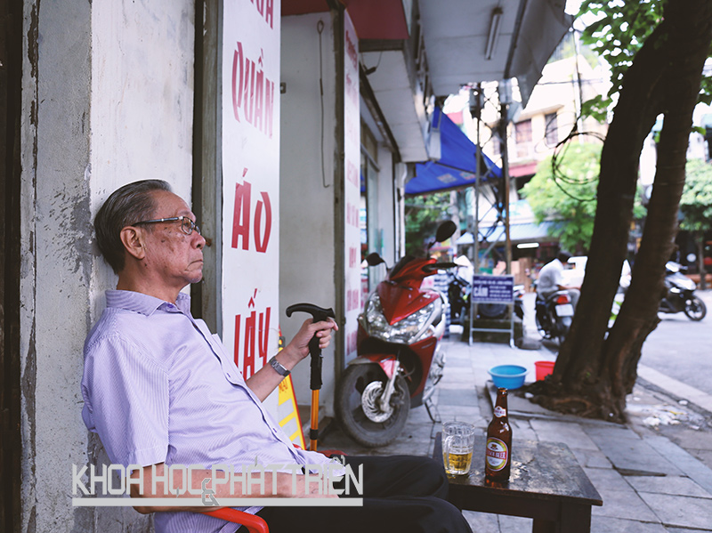 Một cụ già vừa nhâm nhi cốc bia vừa ngắm phố trên vỉa hè phố Đào Duy Từ, Hà Nội. Ảnh: Loan Lê