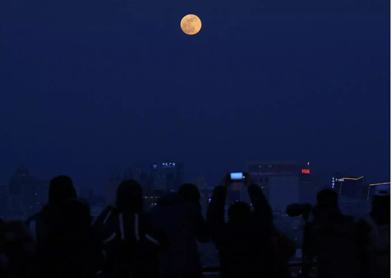 Người dân đang tập trung để quan sát và chụp ảnh siêu trăng xuất hiện phía trên các tòa nhà ở Bắc Kinh, Trung Quốc. Ảnh: EPA.
