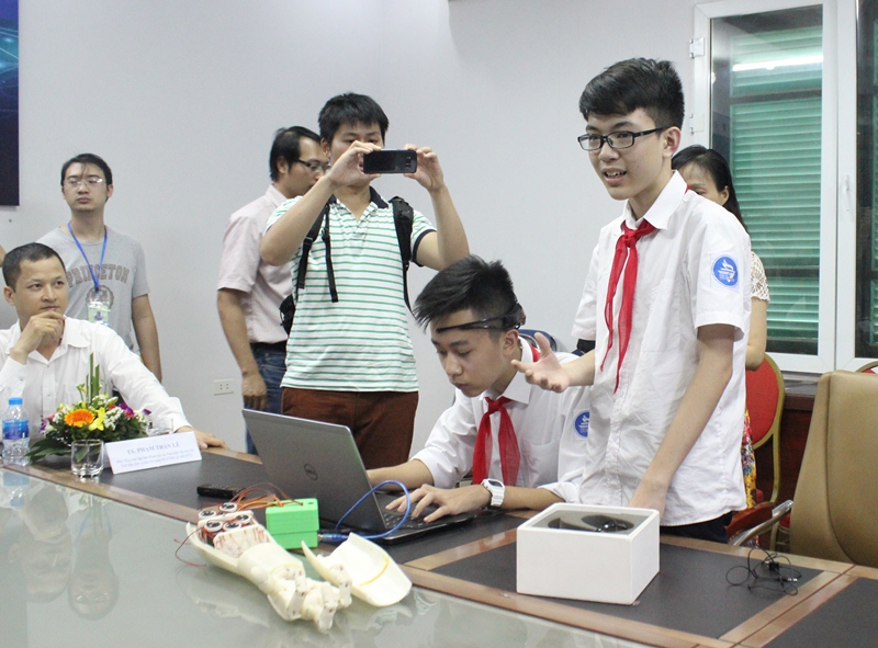 Phan Trường Anh Khôi và Nguyễn Công Huy trình diễn điều khiển cánh tay robot bằng ý nghĩ. Ảnh: Công Nhất