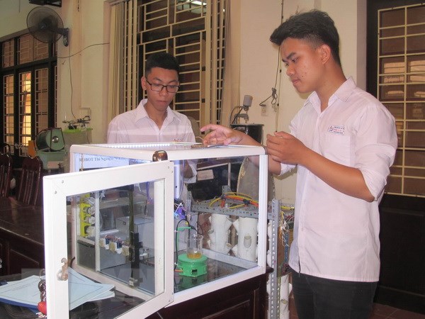 Em Giang Quốc Hoàn và Đỗ Hữu Toàn kiểm tra mô hình robot thí nghiệm hóa học. (Ảnh: Thùy Dung/TTXVN)