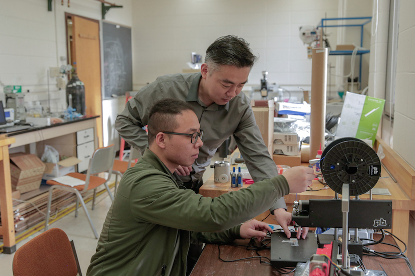 Kỹ sư kiểm nghiệm chính Xudong Wang (đứng) và Sinh viên tốt nghiệp Guang Yao (ngồi) đang điều chỉnh máy in 3D để chế tạo thiết bị cấy ghép giảm cân. (Nguồn: ĐH Wisconsin-Madison)