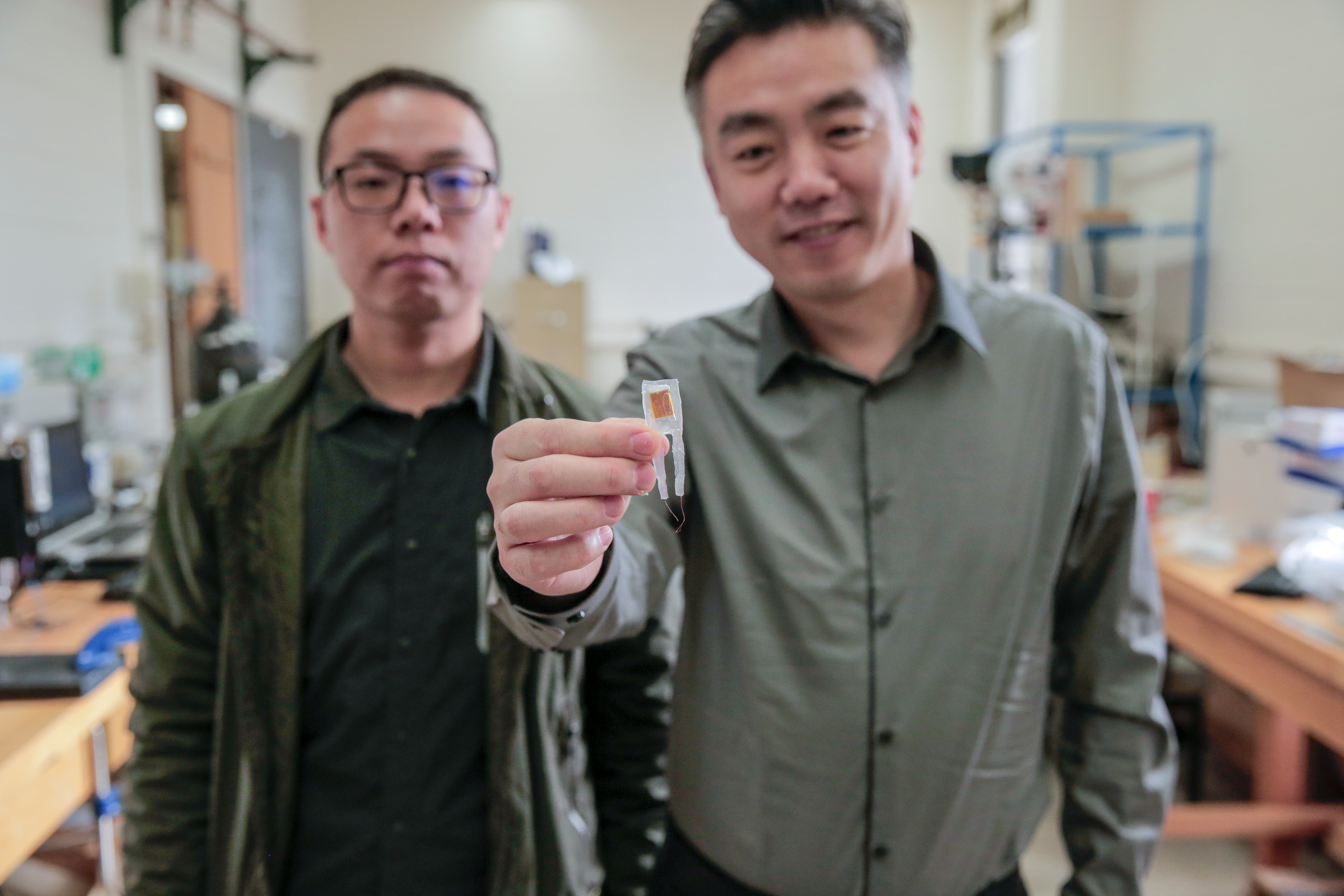Guang Yao (trái) và Xudong Wang (phải) cầm một thiết bị cấy ghép nhỏ đã được thí nghiệp giúp chuột giảm 40% trọng lượng cơ thể. (Nguồn: ĐH Wisconsin-Madison)