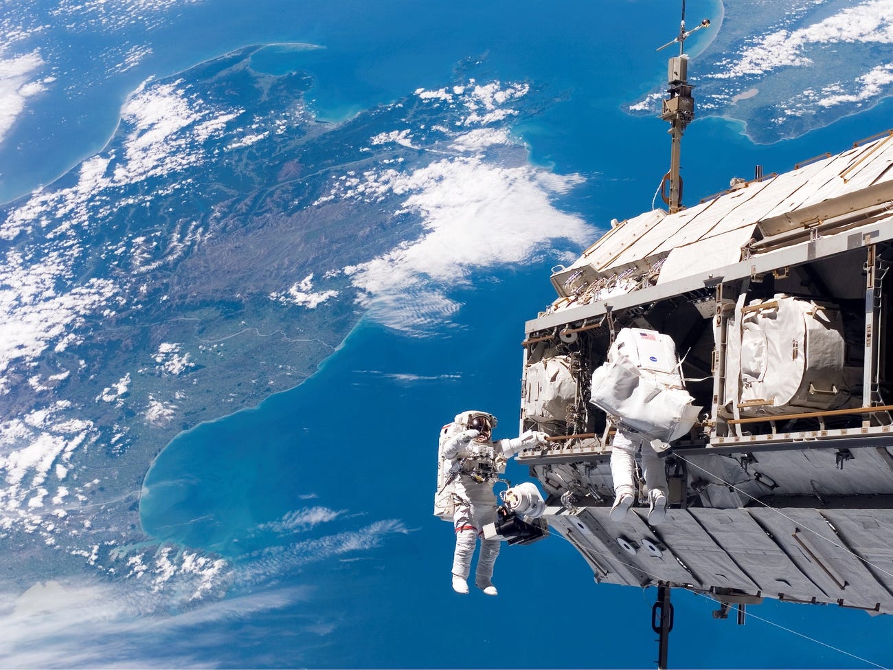 Các nhà du hành vũ trụ Robert L. Curbeam Jr., Christer Fuglesang tham gia một hoạt động ở ngoài tàu vũ trụ, phía dưới là New Zealand và eo biển Cook ở châu Á Thái bình dương. Nguồn: NASA.