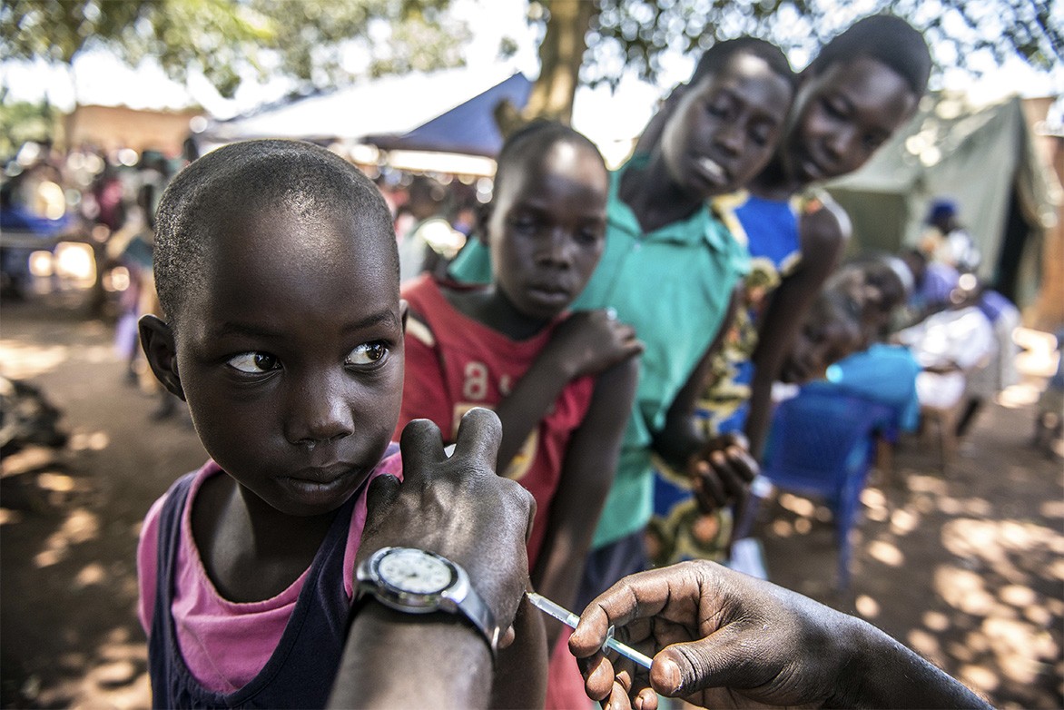 Tiêm vaccine cho trẻ em ở Ochaga, Uganda. Các nước nghèo như Uganda phải nhận hỗ trợ rất nhiều từ WHO để thực hiện theo các hướng dẫn y tế, chống dịch bệnh hiểm nghèo. Ảnh: Tommy Trenchard/Panos 