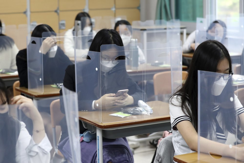 Các em học sinh cuối cấp tại trường trung học Jeonmin ở Daejeon (Hàn Quốc) đang chờ đến giờ vào học. Trước mặt các em là một tấm chắn nhựa trong suốt. Ảnh: Kim Jun-beom / Yonhap via AP)