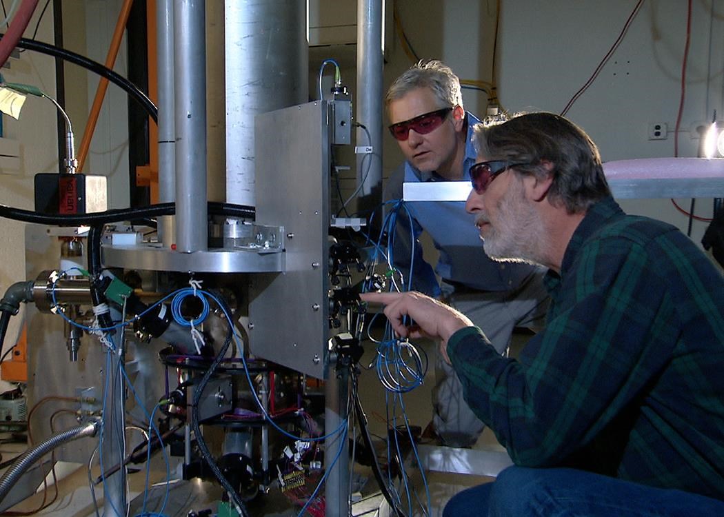 Hai nhà vật lý của NIST là Steve Jefferts (bên phải) và Tom Heavner với đồng hồ hạt nhân NIST-F2, một tiêu chuẩn về thời gian dân sự mới của Mĩ. Nguồn: nbcnews.com