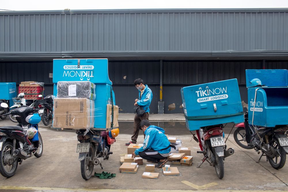 Một nhân viên giao hàng của Tiki.vn đóng gói đơn đặt hàng vào hộp đầu xe máy của mình tại một trong những kho hàng của công ty ở Thành phố Hồ Chí Minh. Nhiếp ảnh gia: Yến Dương / Bloomberg