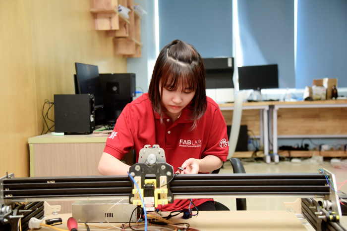 Lã Thị Hường, sinh viên ngành Vật lý kỹ thuật và Điện tử tại Trường ĐH Khoa học và Công nghệ Hà Nội, đang sửa chữa một máy CNC trong FABLAB của trường. Ảnh: USTH, 2021