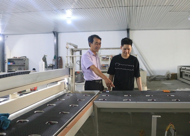 Anh Trần Văn Quyết (bìa trái) giới thiệu mô hình máy cắt kính dán an toàn. Nguồn: qdnd.vn