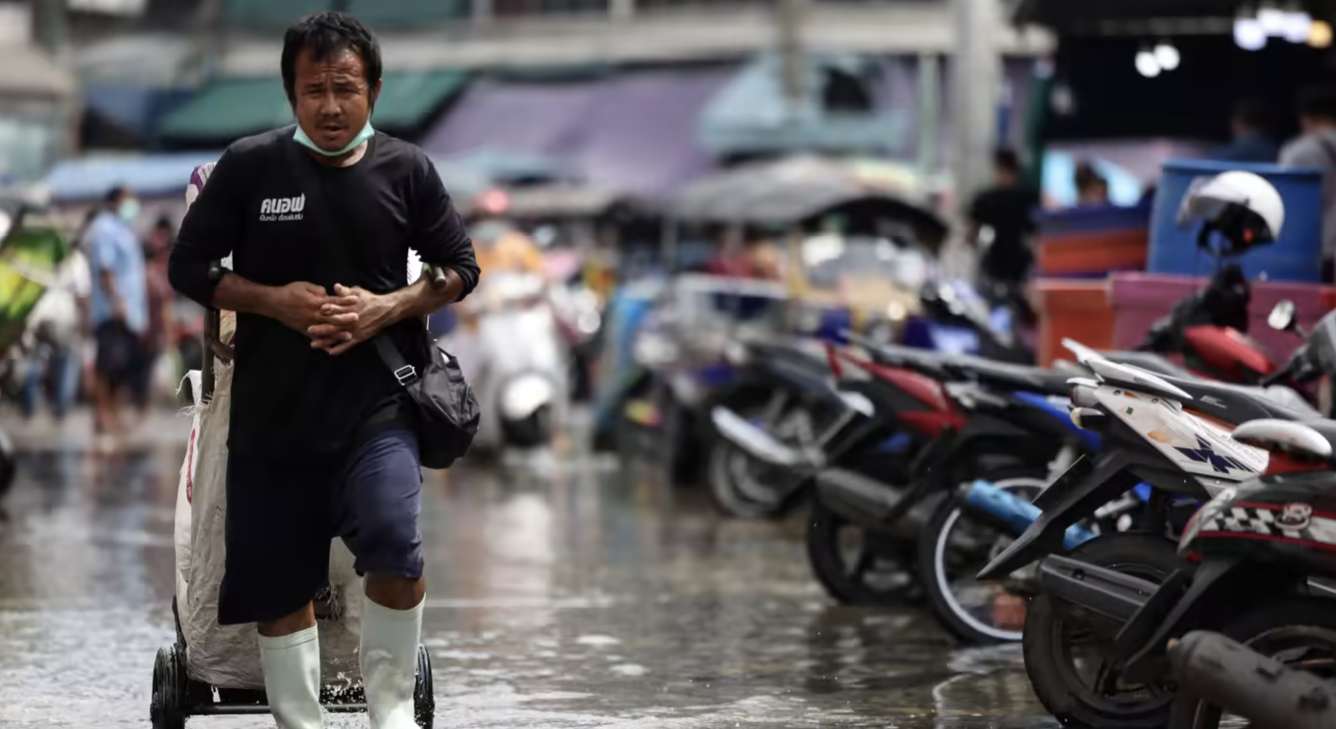 Một người đàn ông đi qua khu chợ ngập nước ở ngoại ô Bangkok vào tháng 11 năm 2021. Các quốc gia châu Á đặc biệt dễ bị ảnh hưởng bởi các mối nguy hiểm liên quan đến thời tiết. © Reuters