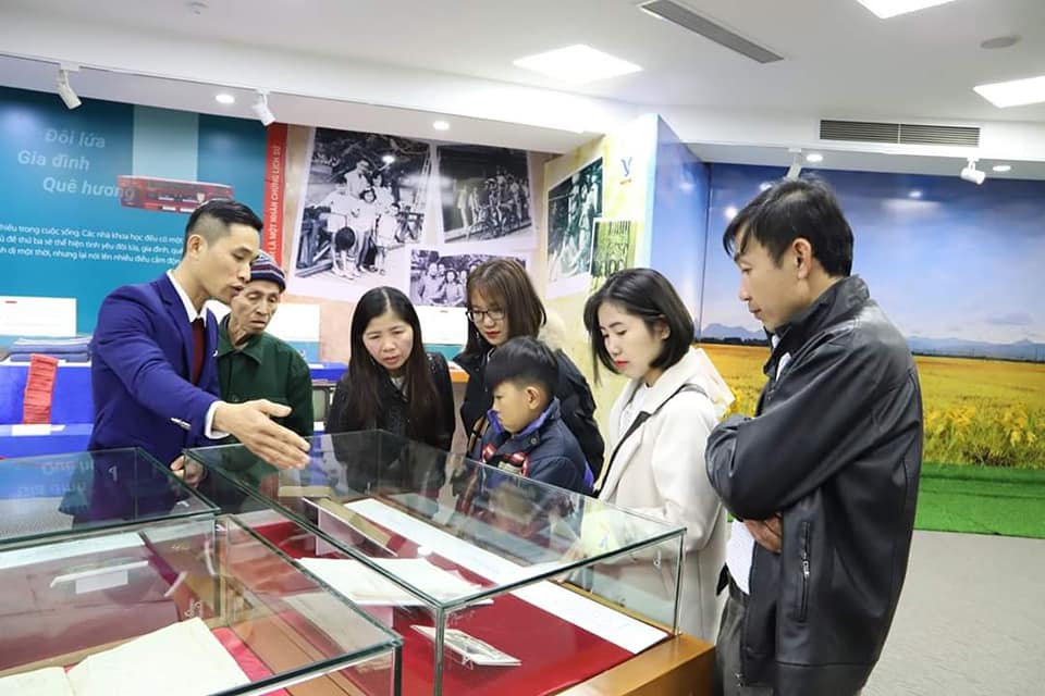 Một gia đình ba thế hệ đang lắng nghe thuyết minh viên giới thiệu về các hiện vật trong khu trưng bày “Thẳm sâu trong từng kỷ vật” thuộc Công viên Di sản các nhà khoa học Việt Nam. Ảnh: MEDDOM.