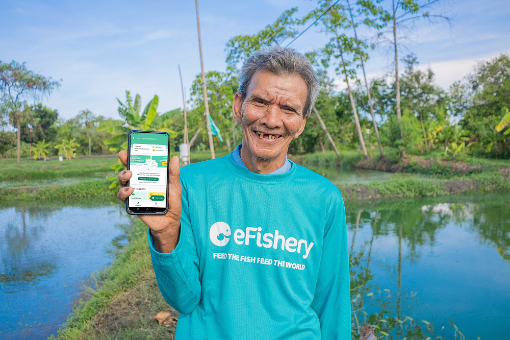 Người nông dân khoe giao diện ứng dụng của eFishery trên máy điện thoại. Nó giúp họ theo dõi việc cho cá ăn từ xa theo thời gian thực. Ảnh: eFishery