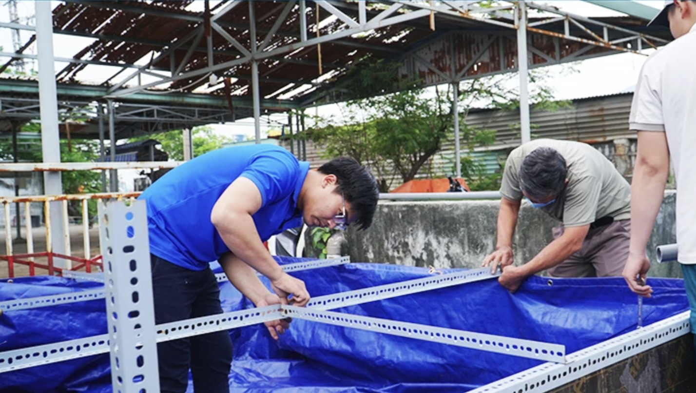 Kỹ sư Nguyễn Quốc Vương (bên trái) đang lắp đặt bể lọc di động tại một đơn vị. Ảnh: Báo Thời nay