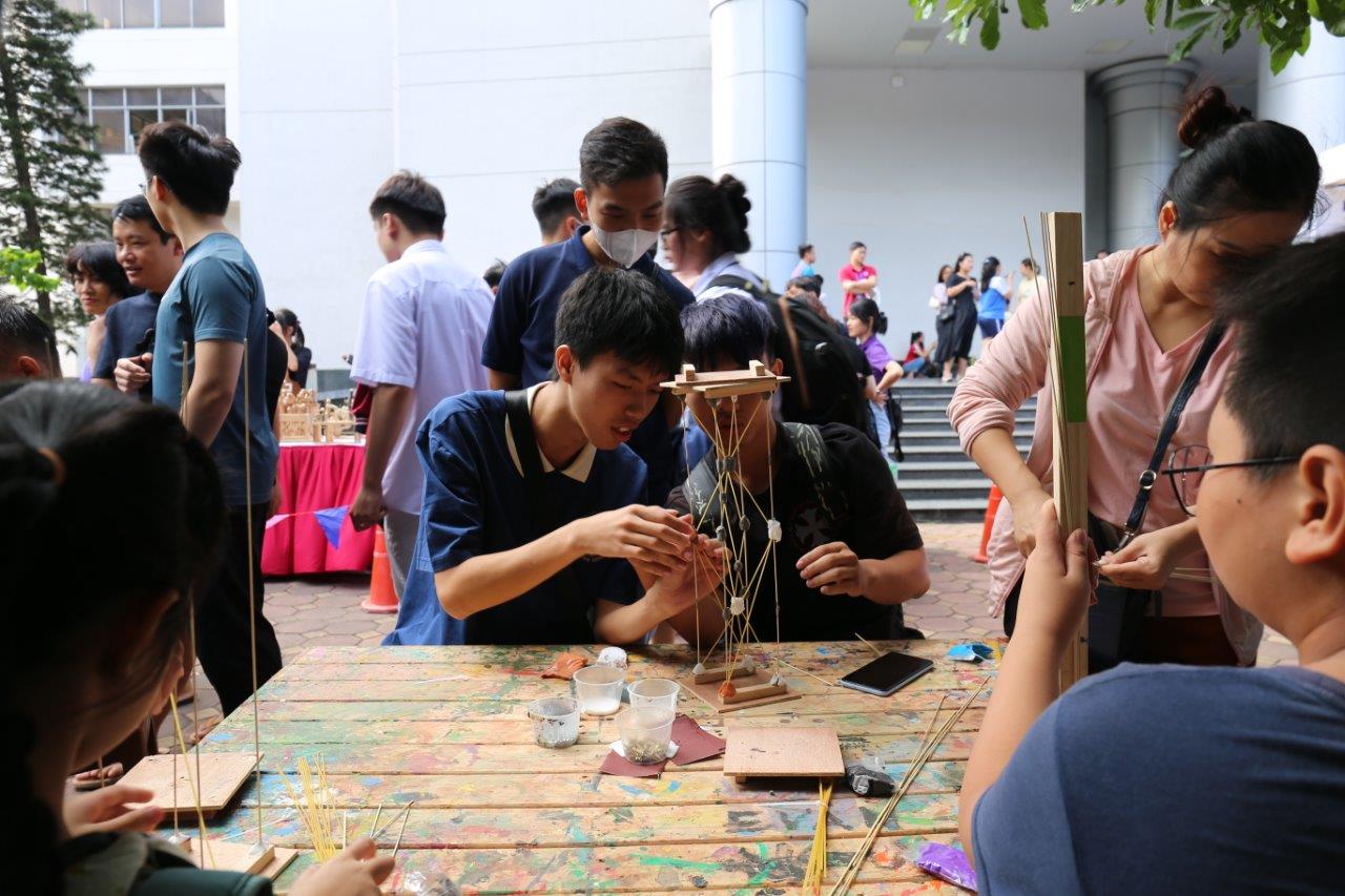 Học sinh và phụ huynh thử làm mô hình nhà chống động đất tại gian hàng của Xưởng sáng tạo Creative Gara. 