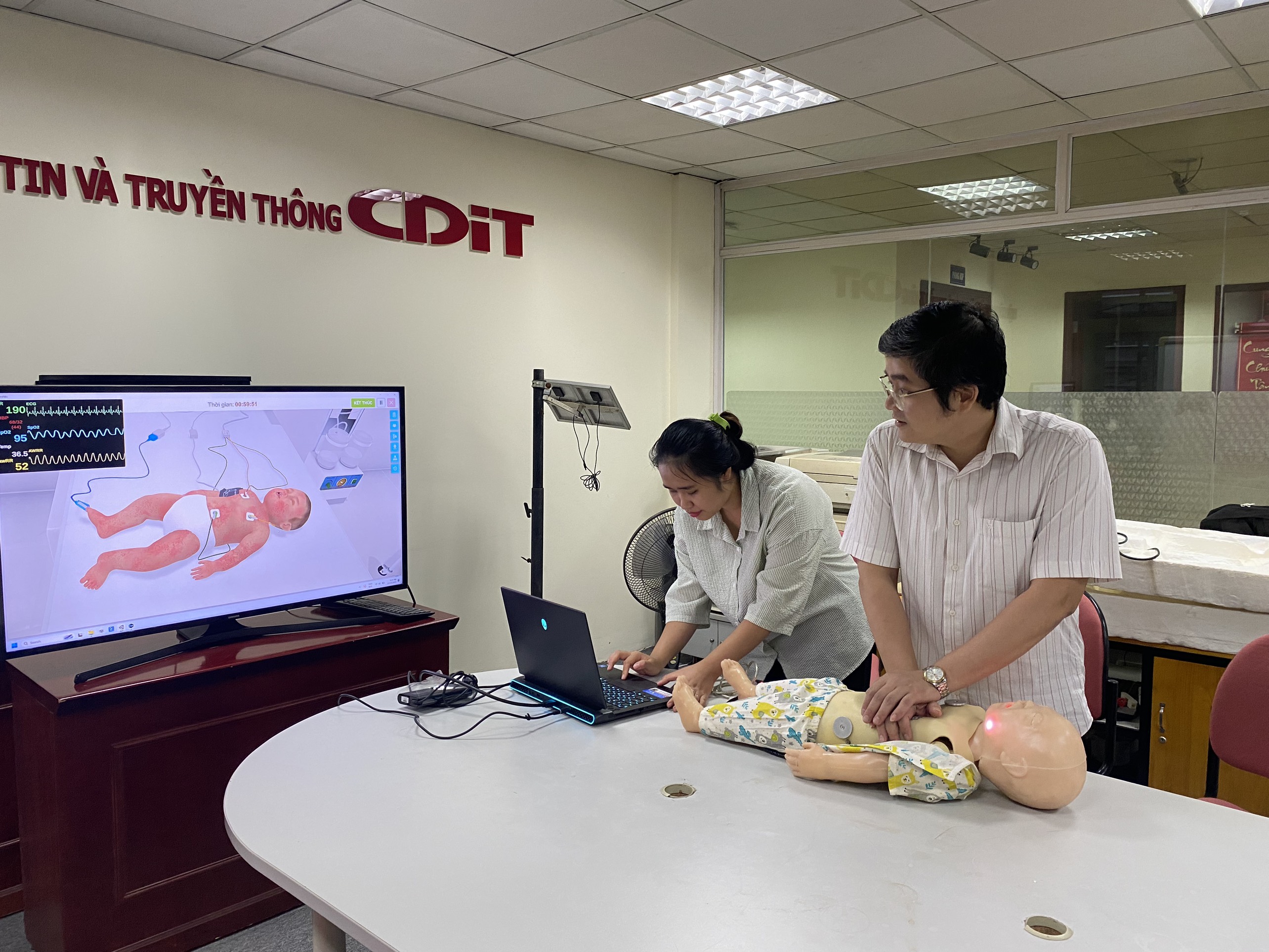 Ths. Nguyễn Đức Hoàng (phải) và trợ lý đang mô phỏng tình huống cấp cứu ép tim ngoài lồng ngực cho bệnh nhi. Ảnh: Ngô Hà