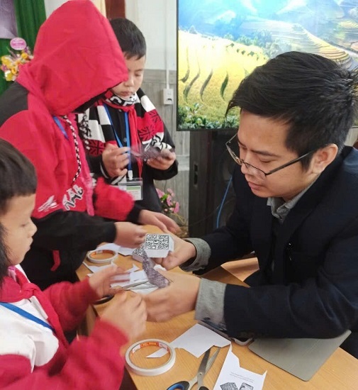Th.S Nguyễn Trung Kiên hướng dẫn học sinh Trường phổ thông dân tộc nội trú THCS, THPT huyện Quản Bạ, thị trấn Tam Sơn, tỉnh Hà Giang, gấp hộp để trải nghiệm công nghệ thực tế ảo tăng cường. Ảnh: Lan Anh