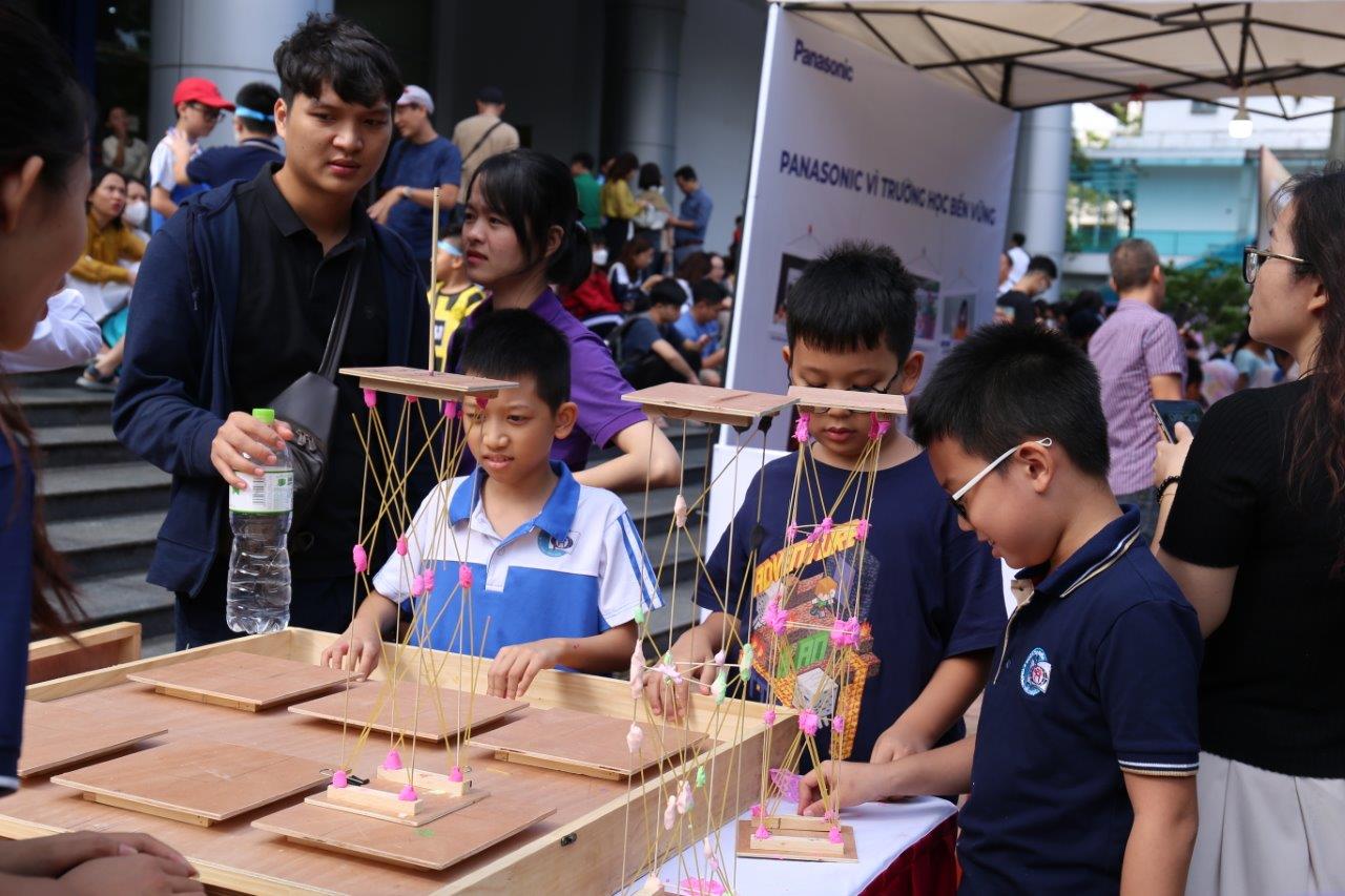 Các em nhỏ thử làm mô hình nhà chống động đất từ gỗ, tre, bó mỳ Ý và đất sét tại Ngày hội STEM 2023 tại ĐH Bách khoa Hà Nội. Ảnh: Ngô Hà